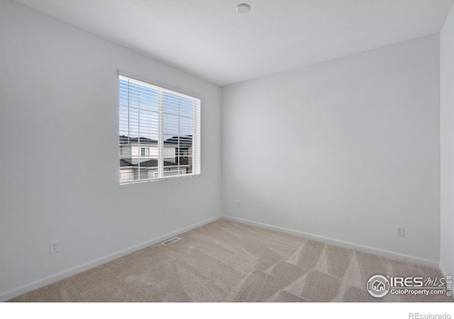 unfurnished room with carpet, visible vents, and baseboards