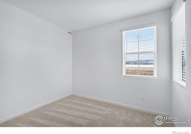 carpeted spare room featuring baseboards