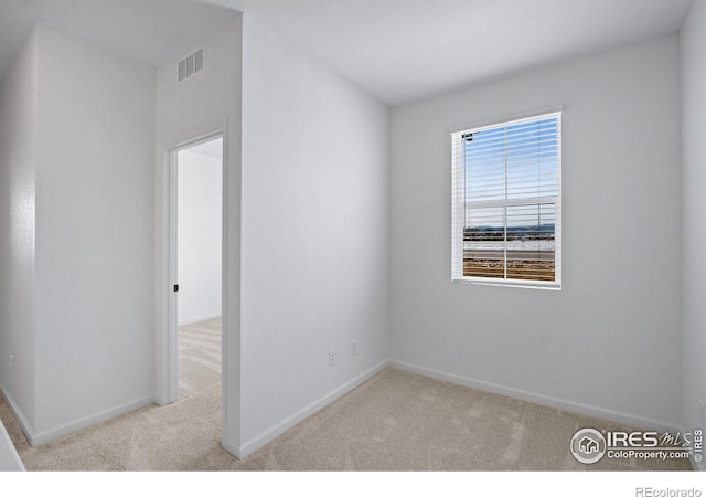 empty room with carpet, visible vents, and baseboards