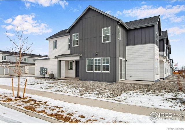 view of front of property featuring central AC unit, a garage, a shingled roof, board and batten siding, and a patio area