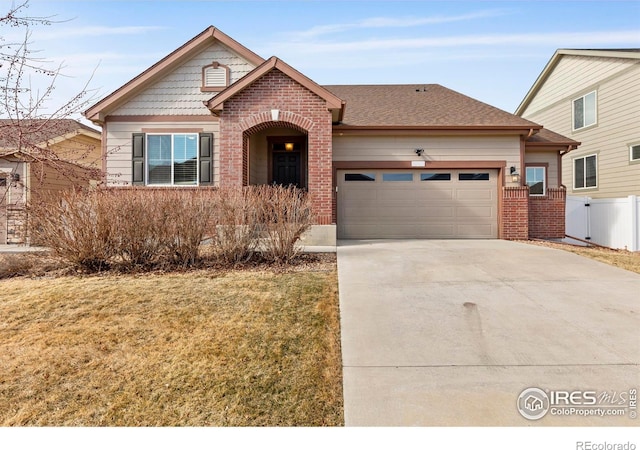 view of front of property with a garage, brick siding, fence, concrete driveway, and roof with shingles