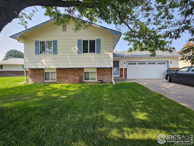 split level home with a garage, concrete driveway, brick siding, and a front lawn