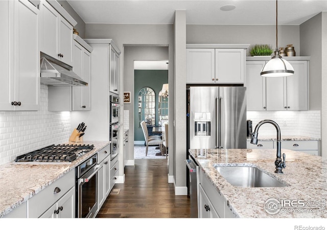 kitchen featuring dark wood-style floors, decorative light fixtures, appliances with stainless steel finishes, a sink, and under cabinet range hood