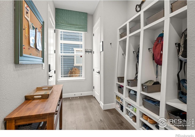 mudroom featuring visible vents, a textured wall, baseboards, and wood finished floors