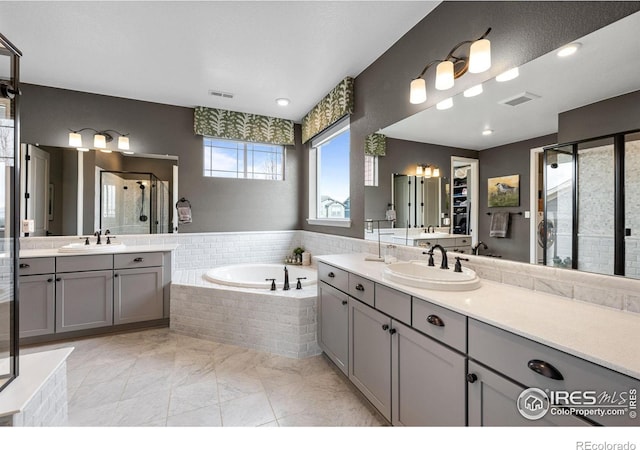 bathroom with a bath, a stall shower, a sink, and visible vents