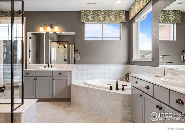 bathroom featuring a stall shower, plenty of natural light, a sink, and a bath