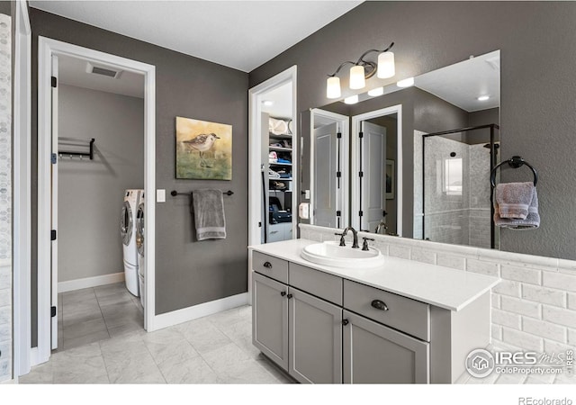 bathroom featuring a stall shower, baseboards, visible vents, independent washer and dryer, and vanity