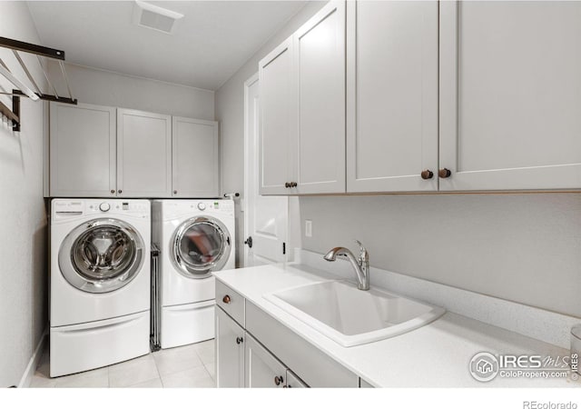 washroom featuring cabinet space, a sink, washing machine and clothes dryer, and light tile patterned flooring