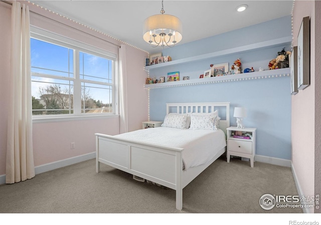 carpeted bedroom featuring baseboards and a chandelier