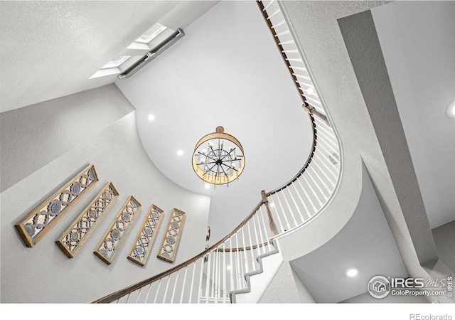 stairway featuring a textured ceiling, a skylight, and high vaulted ceiling