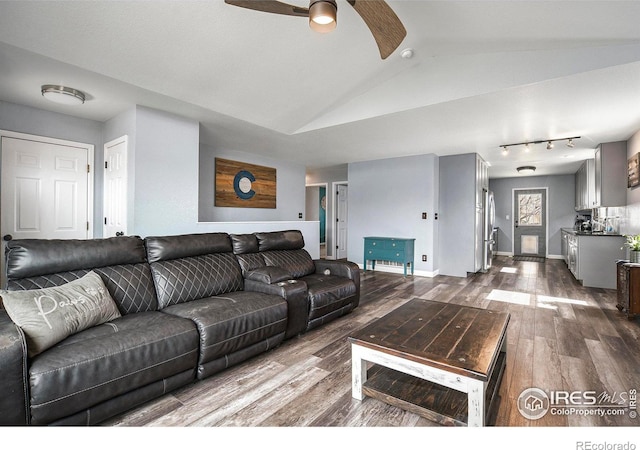 living area featuring dark wood-type flooring, vaulted ceiling, baseboards, and ceiling fan