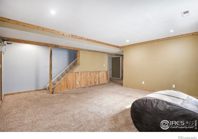 interior space with carpet floors, wood walls, visible vents, stairway, and wainscoting