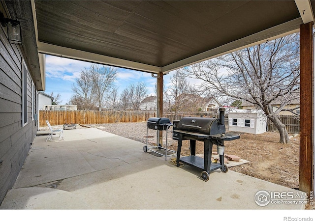 view of patio / terrace featuring a fenced backyard, a grill, and an outbuilding