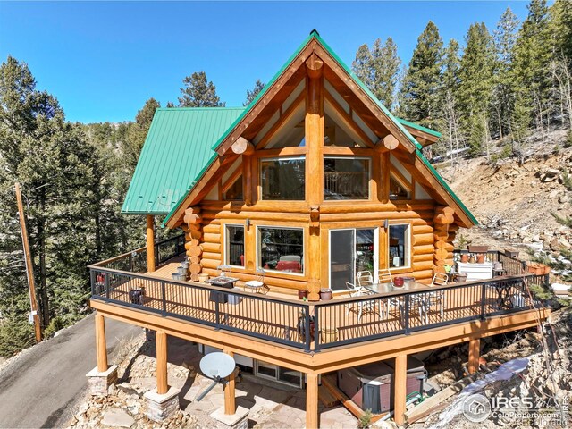 back of property featuring a deck, log siding, and metal roof