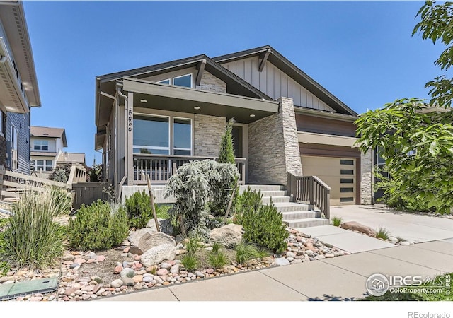 5626 Four Leaf Dr, Longmont, CO 80503 - view of front of house featuring stone siding, a garage, covered porch, board and batten siding, and driveway