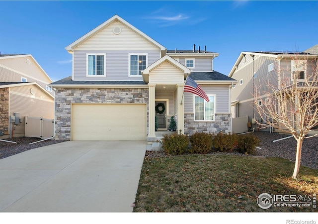 traditional-style house featuring a garage, stone siding, fence, and concrete driveway