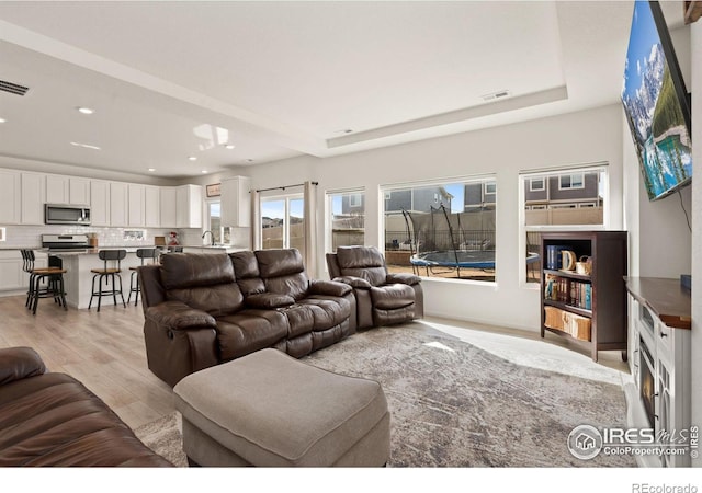 living area with light wood-style floors, visible vents, and recessed lighting