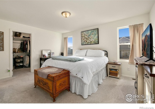 bedroom with baseboards, a spacious closet, a closet, and light colored carpet