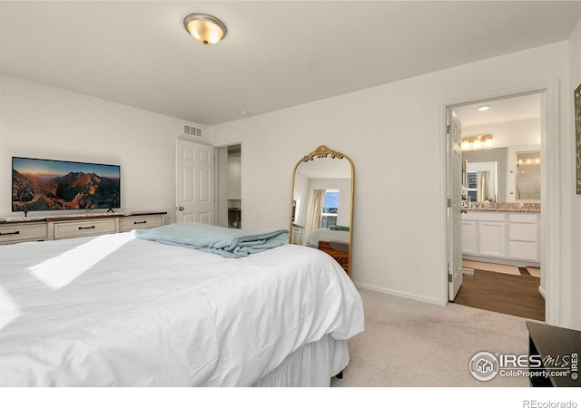 carpeted bedroom featuring baseboards, visible vents, and ensuite bath