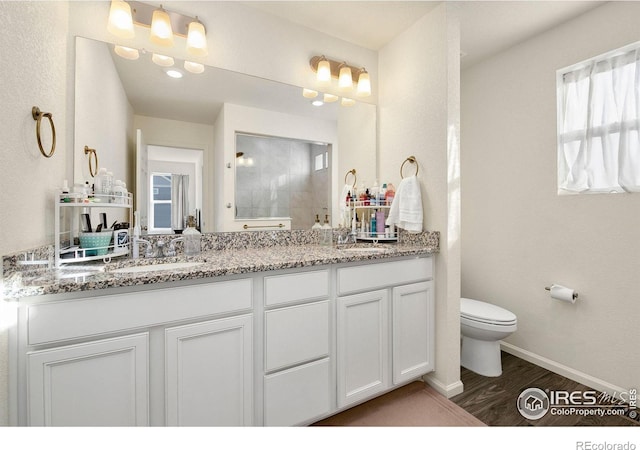 bathroom with double vanity, toilet, a sink, and wood finished floors