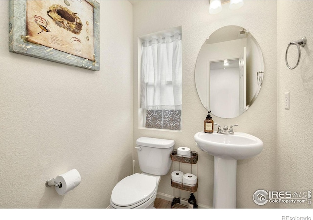 half bathroom featuring baseboards, a sink, and toilet