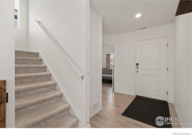 entryway with stairs, visible vents, light wood-style flooring, and recessed lighting