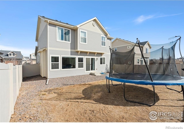 rear view of property with a trampoline and fence