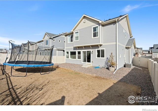 back of house with central air condition unit, a fenced backyard, a trampoline, and a residential view