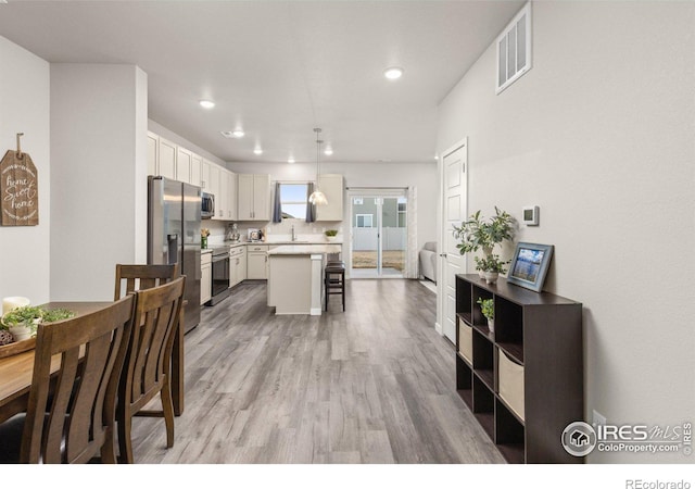 kitchen featuring a breakfast bar, white cabinetry, light countertops, appliances with stainless steel finishes, and light wood-type flooring