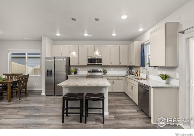 kitchen with wood finished floors, stainless steel appliances, a sink, and a center island