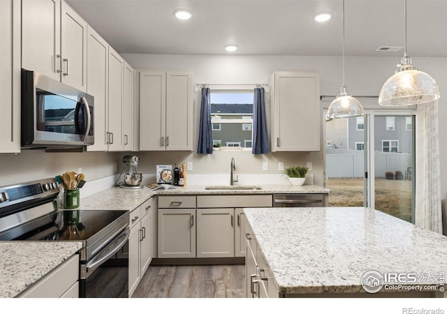 kitchen with light stone countertops, stainless steel appliances, light wood-type flooring, a sink, and recessed lighting