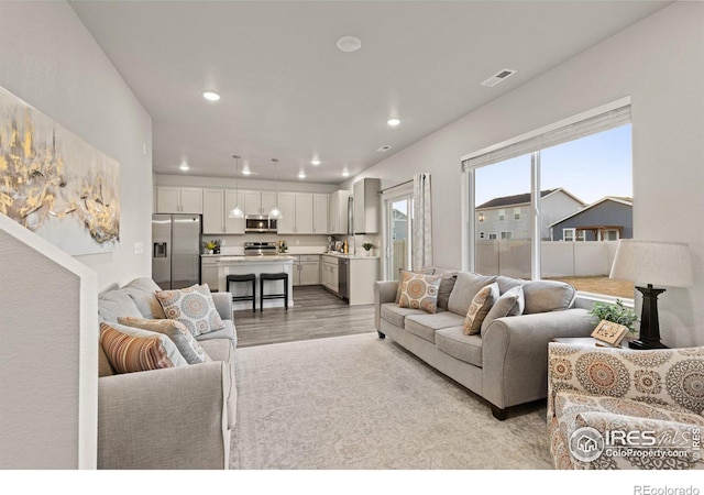 living room with light wood-type flooring, visible vents, and recessed lighting