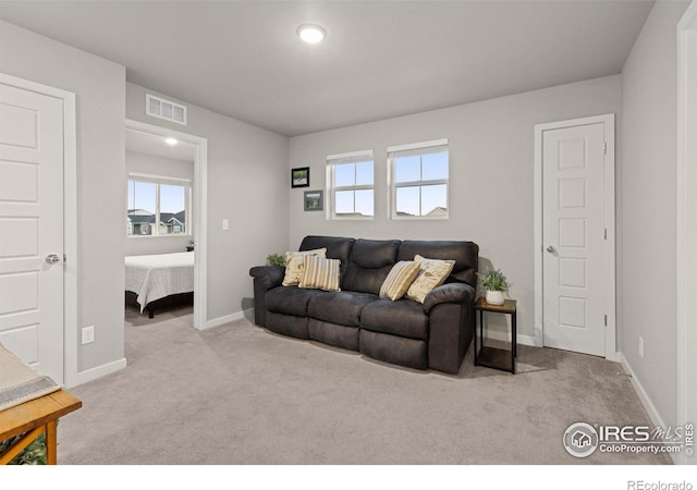 carpeted living room featuring a healthy amount of sunlight, visible vents, and baseboards