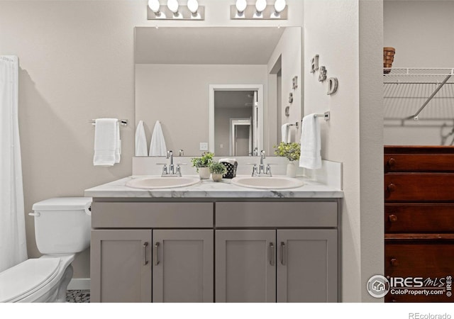 bathroom featuring double vanity, a sink, and toilet