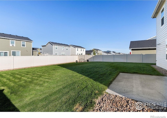 view of yard with a patio, a fenced backyard, and a residential view