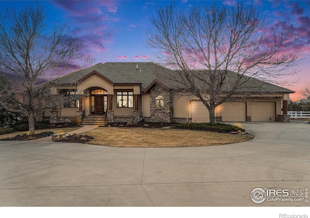 view of front of home featuring concrete driveway, stone siding, an attached garage, fence, and stucco siding