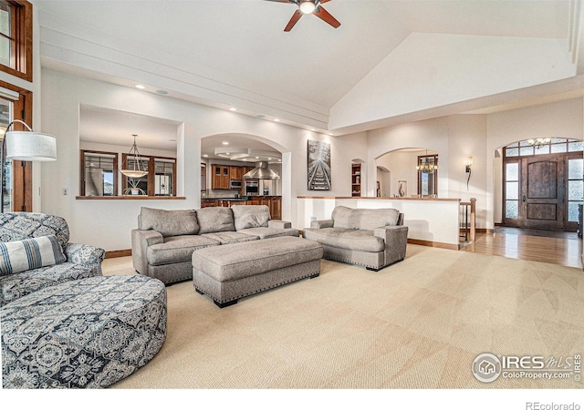 living area featuring arched walkways, recessed lighting, ceiling fan, high vaulted ceiling, and baseboards