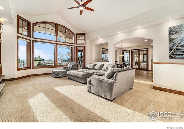 carpeted living area featuring a healthy amount of sunlight, high vaulted ceiling, baseboards, and arched walkways