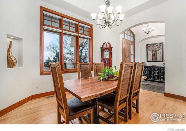 dining space with a chandelier, light wood finished floors, visible vents, and baseboards