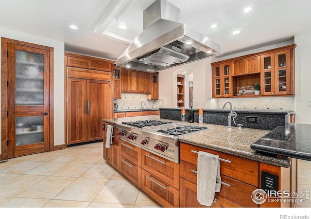 kitchen with island range hood, a spacious island, brown cabinets, stainless steel gas stovetop, and paneled fridge