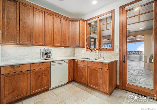 kitchen with decorative backsplash, white dishwasher, a sink, and brown cabinets