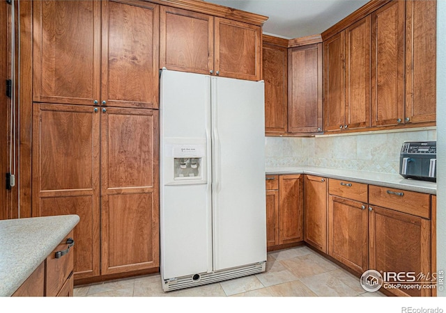 kitchen featuring white fridge with ice dispenser and brown cabinets