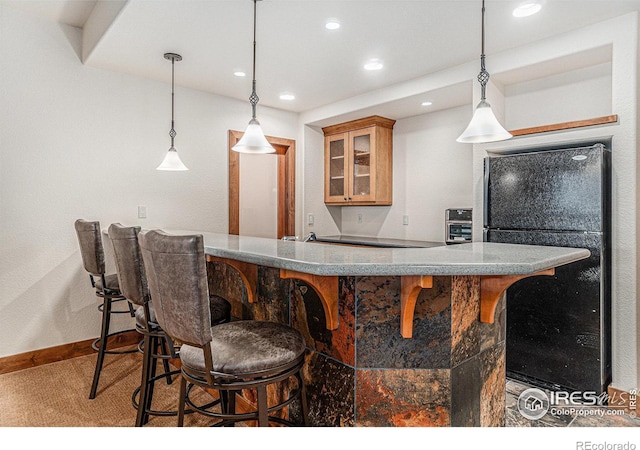 interior space featuring bar, recessed lighting, baseboards, freestanding refrigerator, and pendant lighting