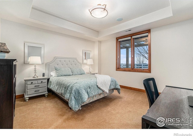 bedroom with light carpet, visible vents, a tray ceiling, and baseboards