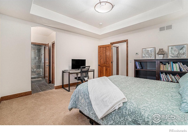 bedroom featuring arched walkways, carpet floors, visible vents, baseboards, and a raised ceiling