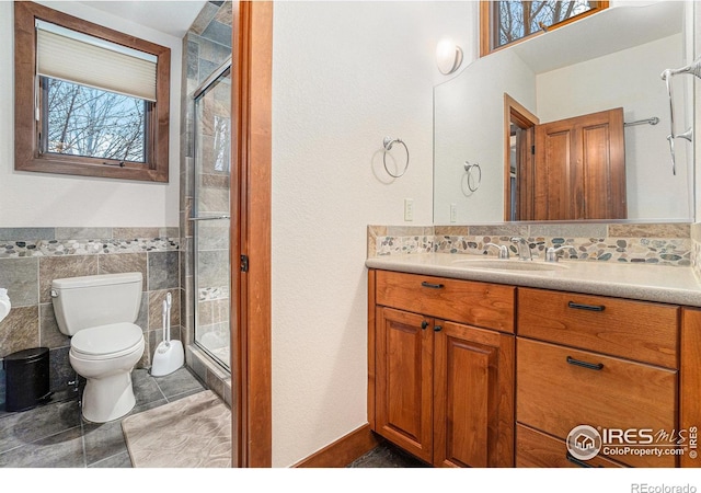 bathroom featuring a stall shower, tile walls, vanity, and toilet