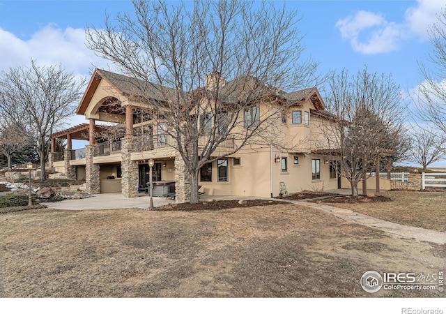 rear view of house with a patio area, fence, a balcony, and stucco siding