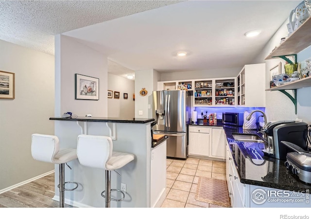 kitchen featuring appliances with stainless steel finishes, a sink, a kitchen breakfast bar, and open shelves