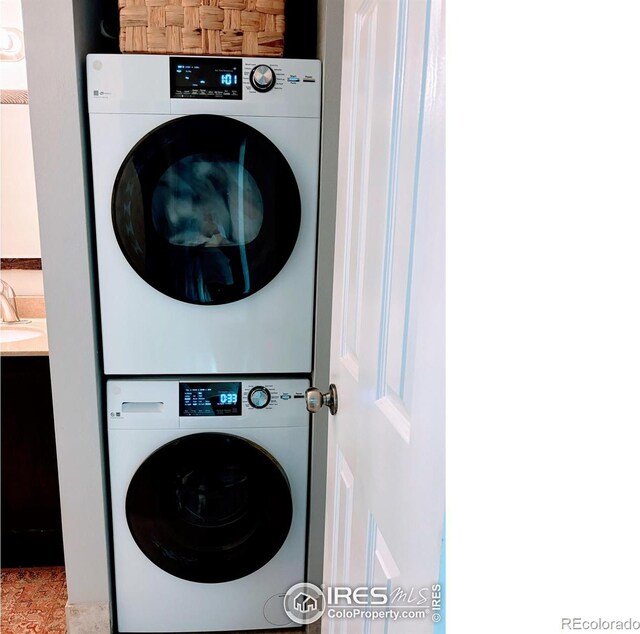 laundry area with laundry area, stacked washer and clothes dryer, and a sink