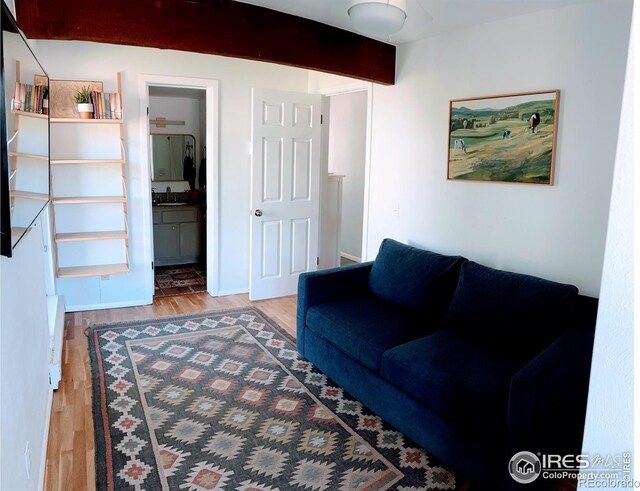 living area featuring beamed ceiling and wood finished floors